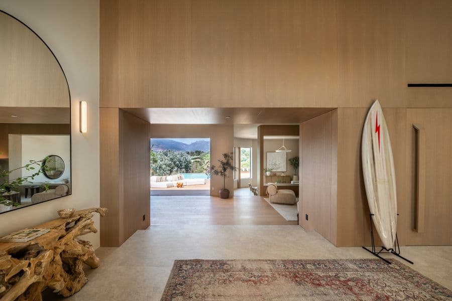 Entry hall lined floor to ceiling in oak panels, with a flush concealed door and an opening through to the living room