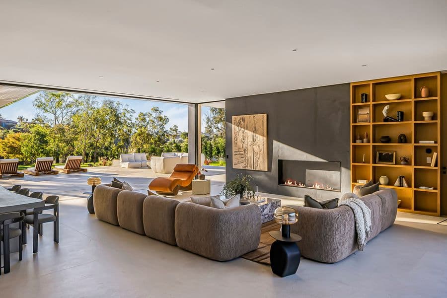 Open living room with a full-height ochre lacquered shelving unit beside a plaster wall with a linear fireplace