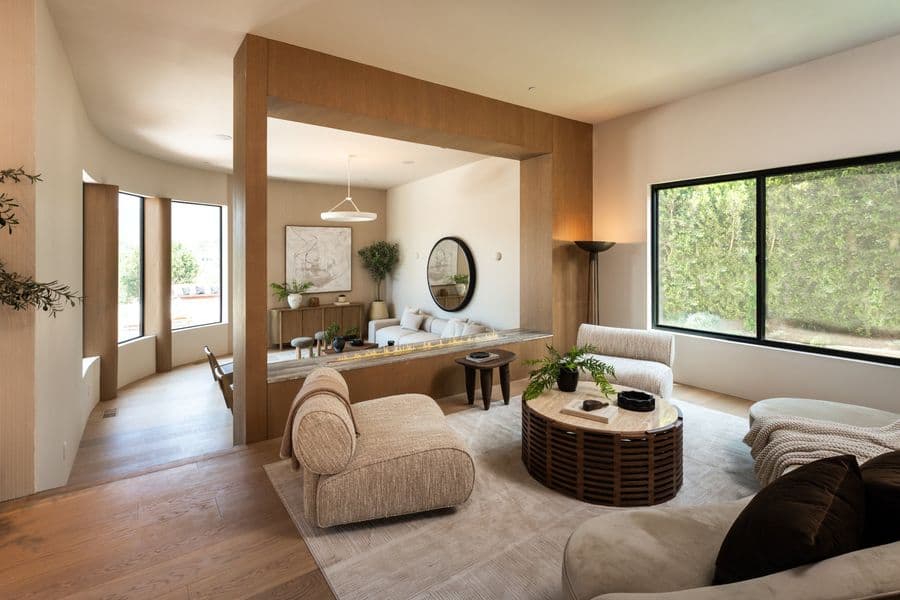 Living room framed by a deep oak-clad portal and fireplace surround, custom millwork by The Pacifica Mill, with curved sofas and a large window