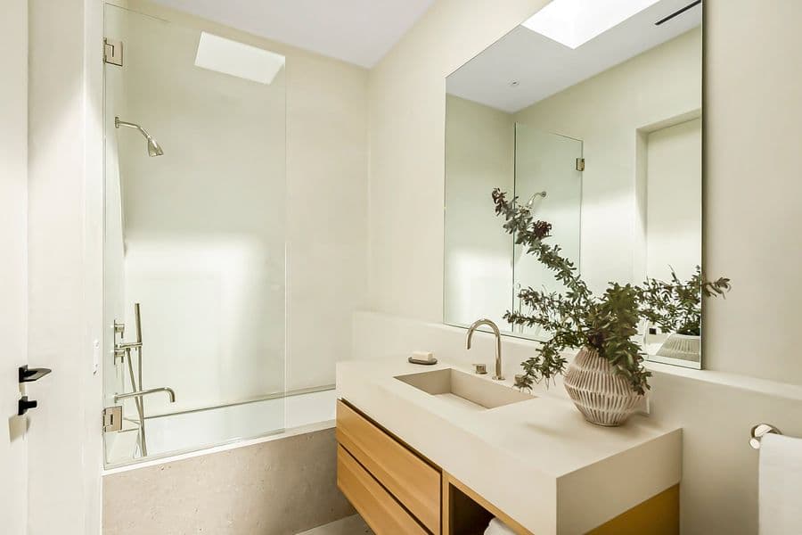 Custom floating oak powder-room vanity with drawers under an integrated plaster sink, with a wall-mounted faucet and mirror